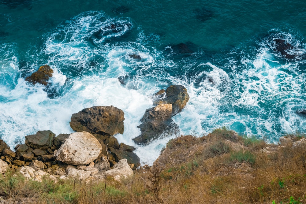 brown rocky shore with blue water waves during daytime