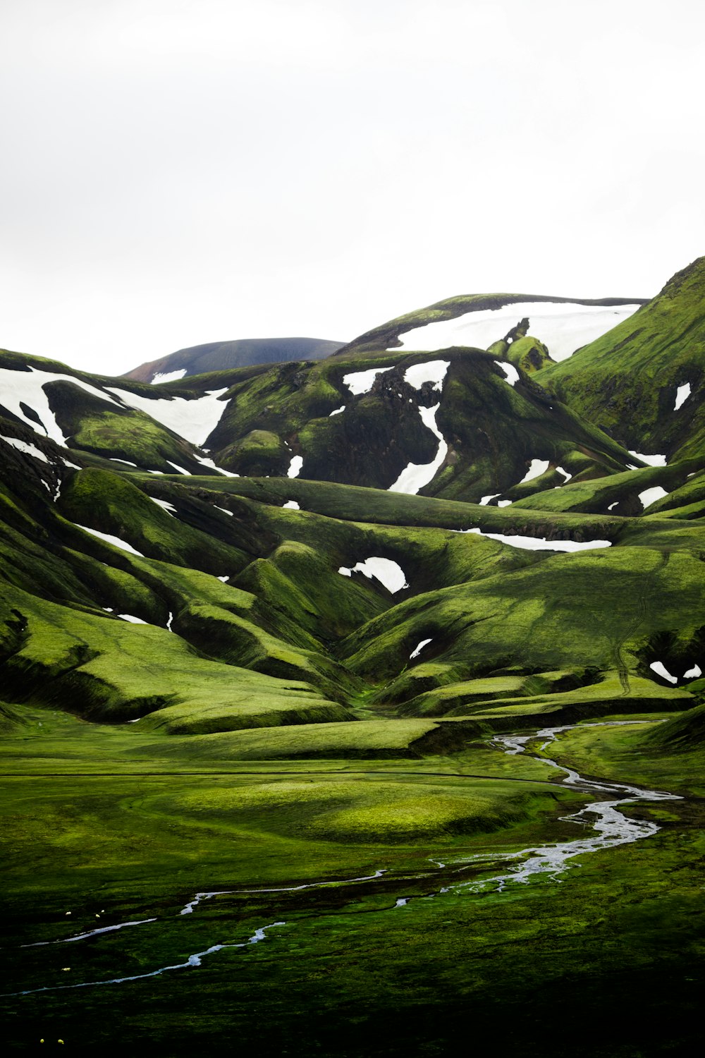 green grass covered mountain under white sky during daytime