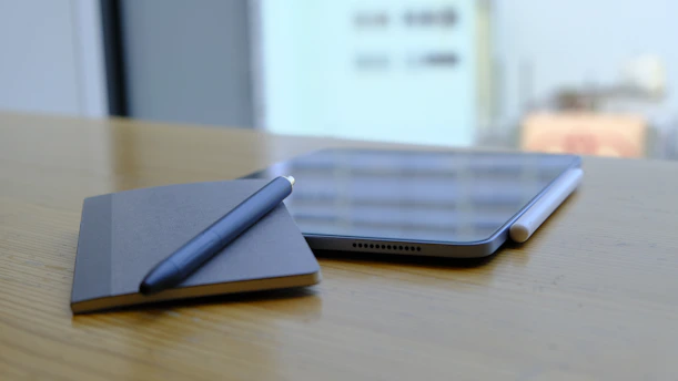 Close-up of a sleek digital notebook with a stylus on a wooden desk, surrounded by cozy ambient lighting