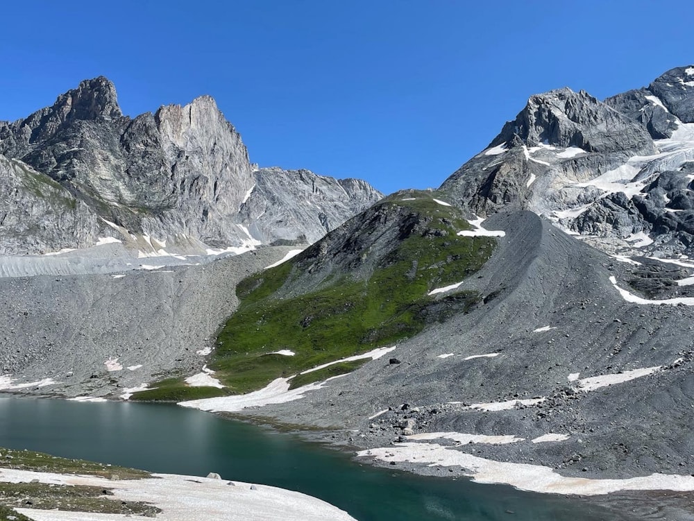 snow covered mountain near lake under blue sky during daytime