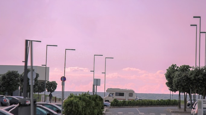 A secure parking lot near the sunny Arenales del Sol beach with caravans and boats parked.