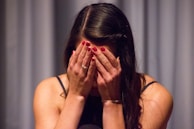 woman in black tank top covering her face with her hands