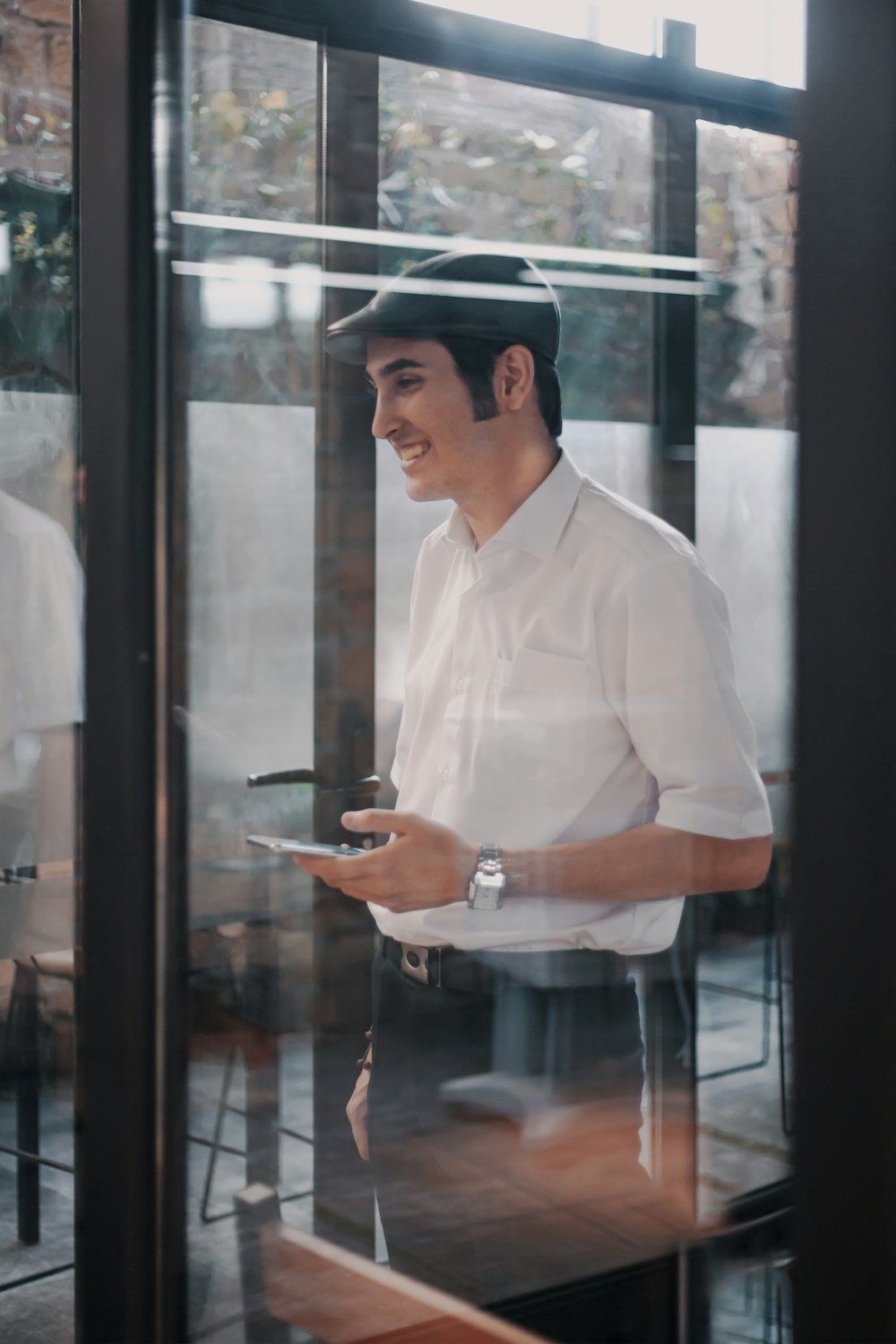 man in white button up shirt standing near glass window