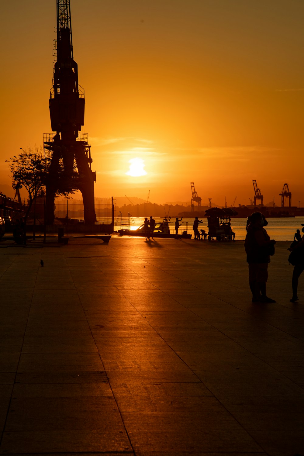 silhouette of people standing on gray concrete floor during sunset