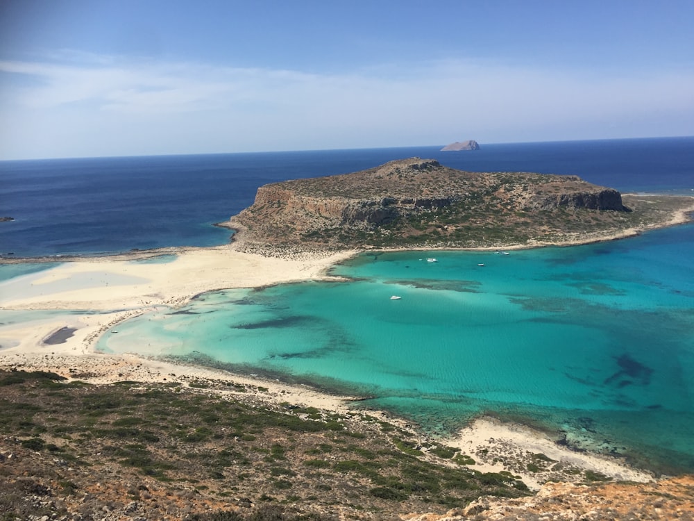 green and brown island in the middle of blue sea during daytime