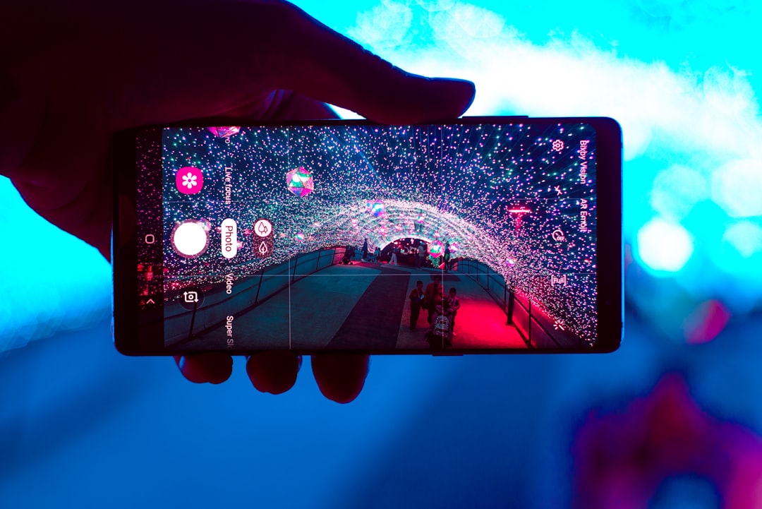 person holding black smartphone with blue and purple light