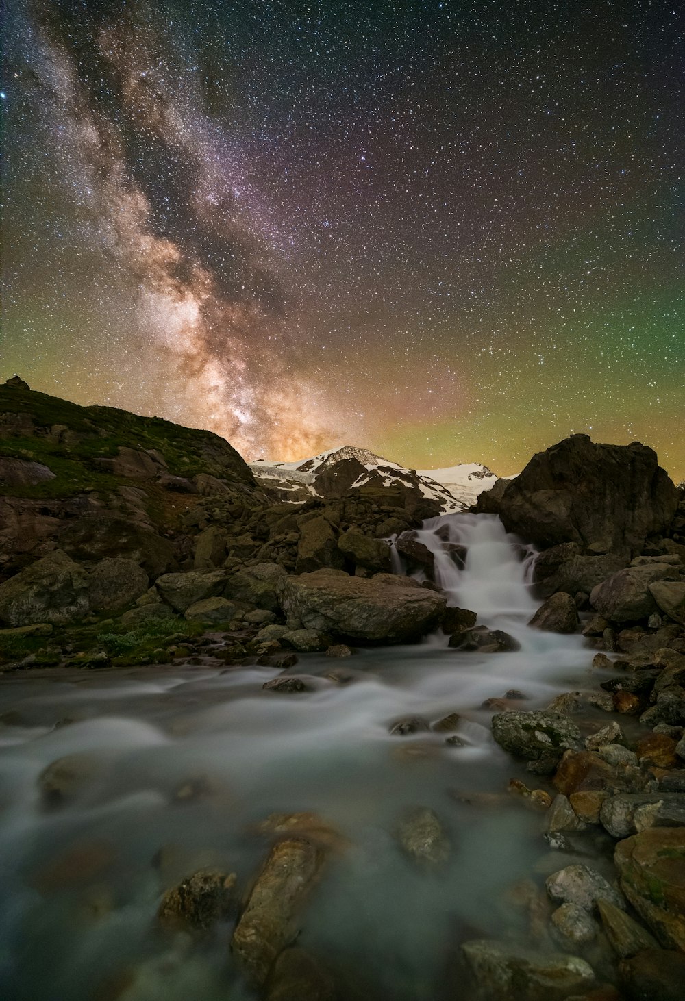 rocky mountain near body of water under starry night