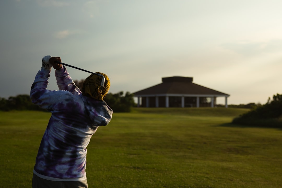 man in blue jacket playing golf during daytime