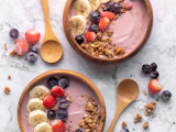 Bols garnis de banane, de fruits rouges et de granola