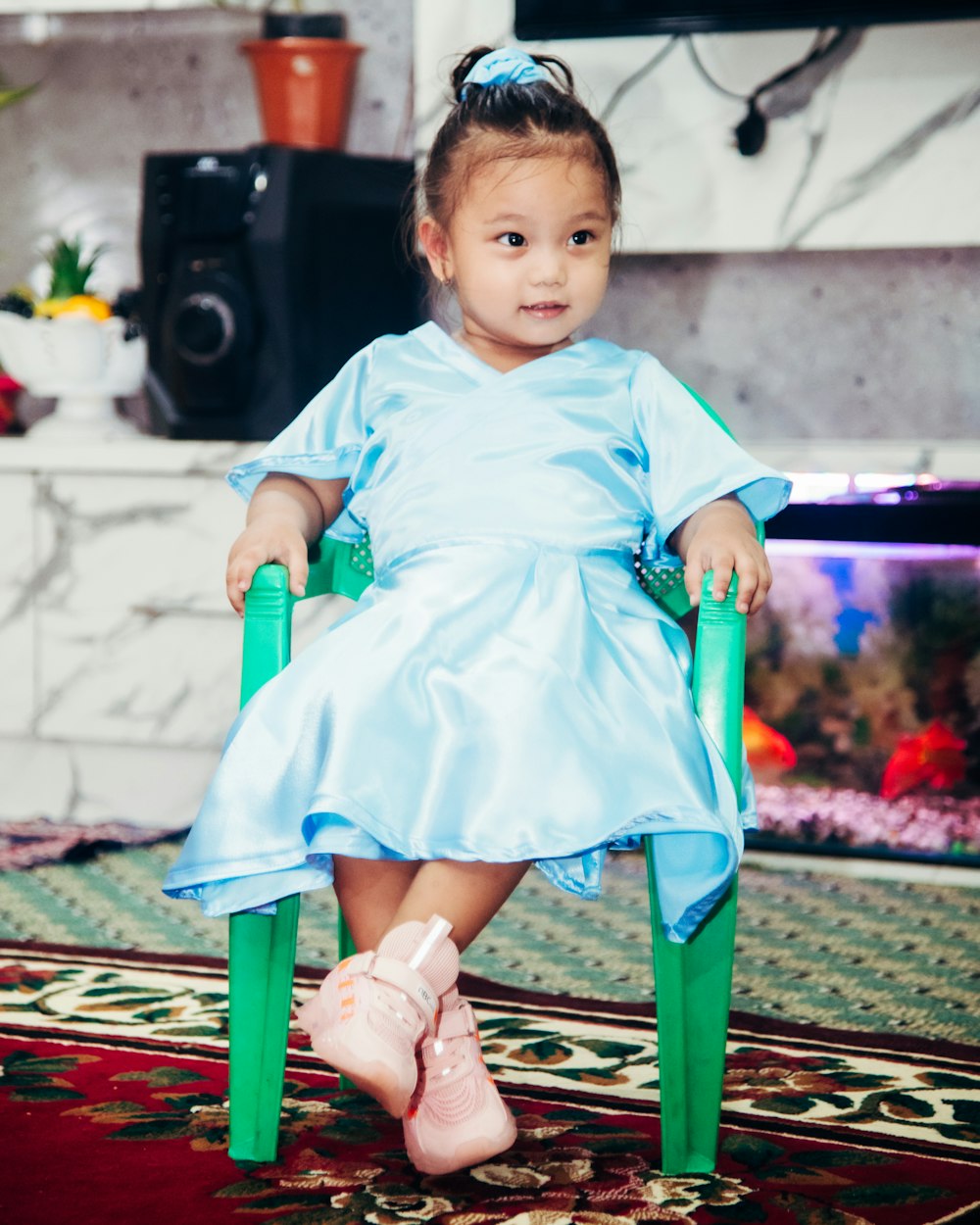 girl in blue dress sitting on green chair