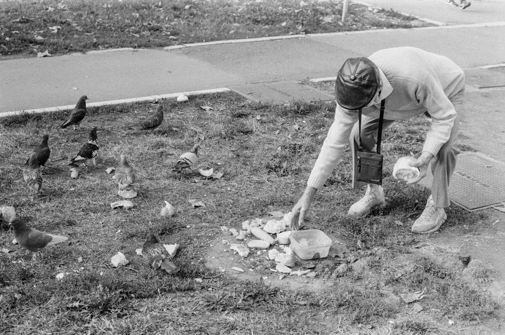 grayscale photo of man in t-shirt and shorts holding garbage bag