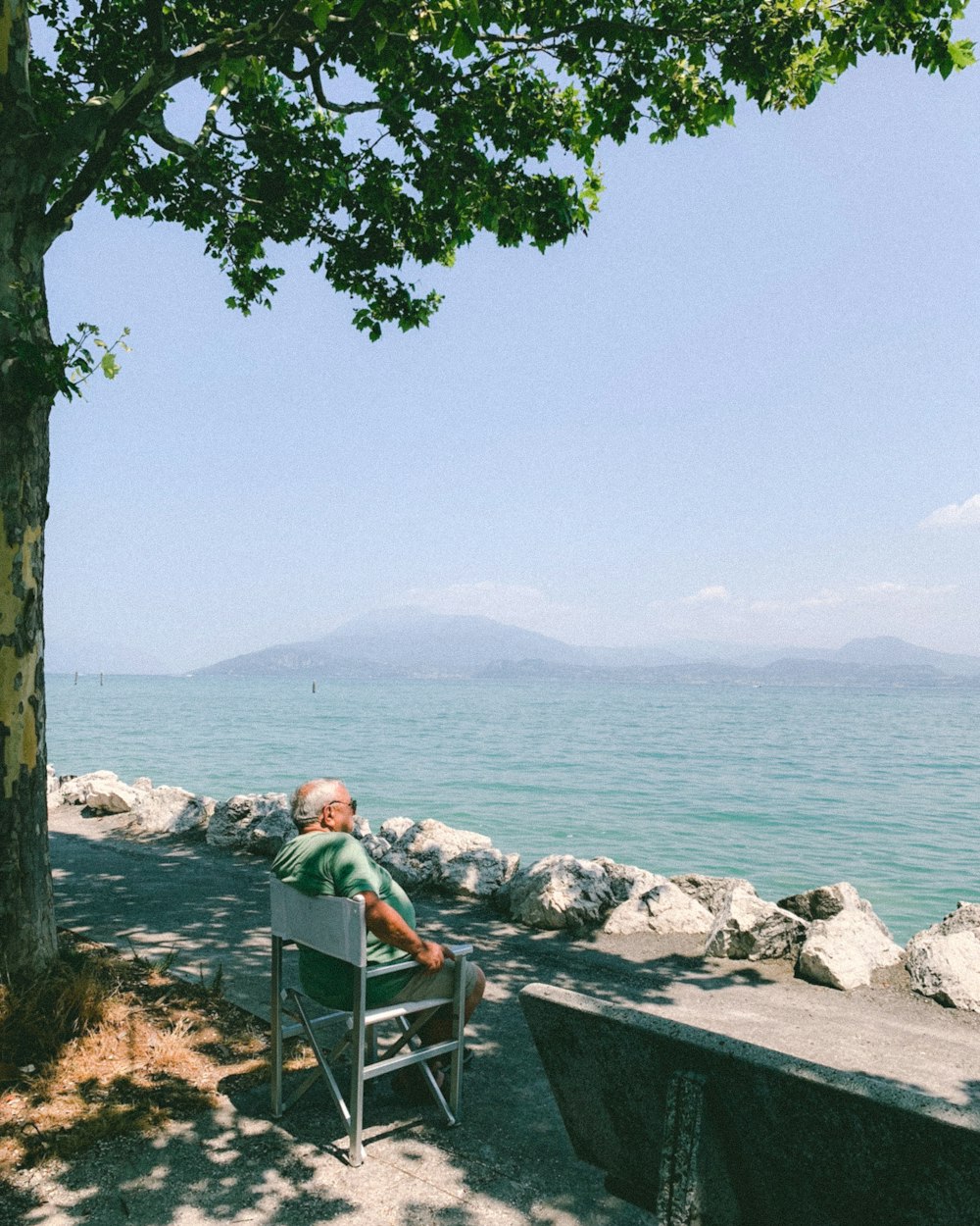 man and woman sitting on bench near body of water during daytime