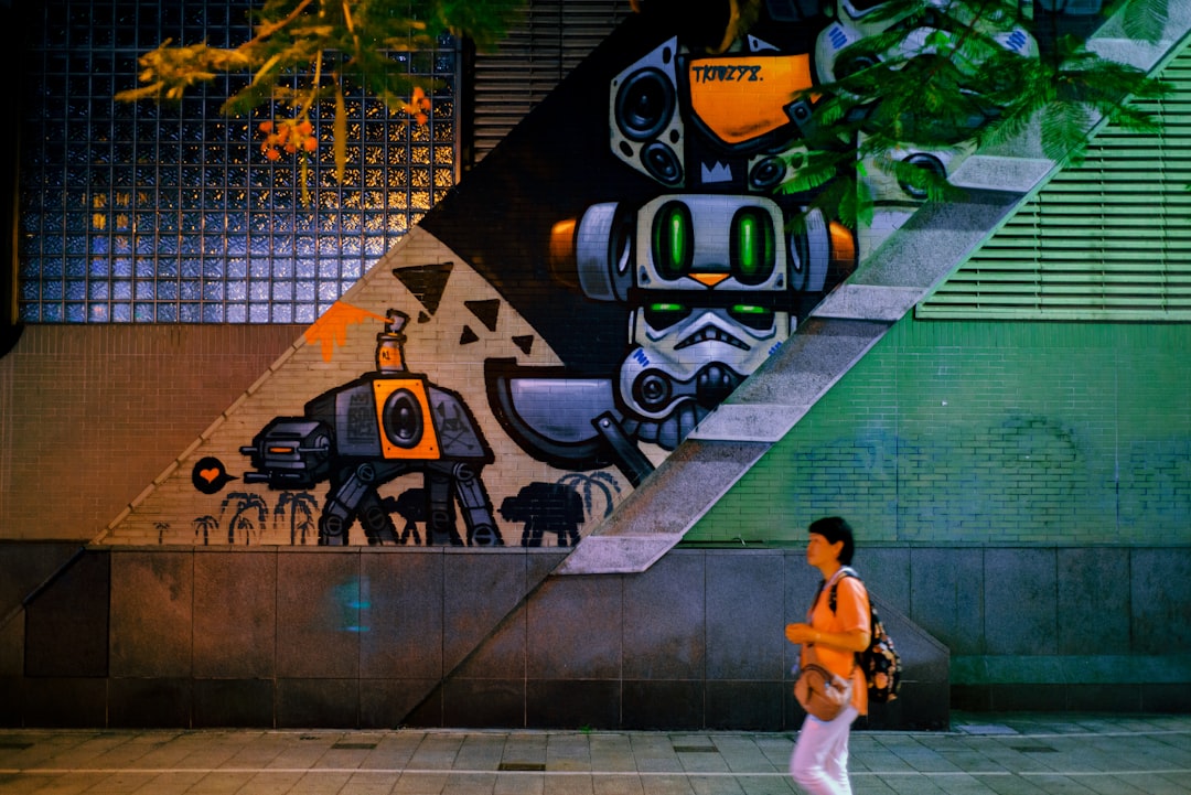 man in white t-shirt and white shorts standing beside wall with graffiti