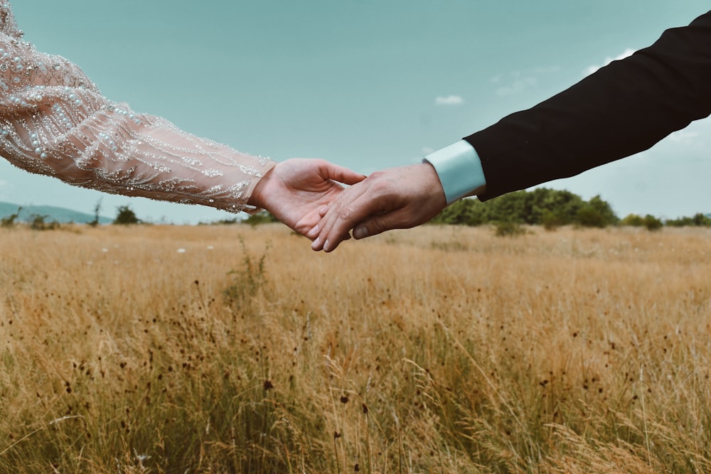 person in white floral dress holding hands with man in black suit