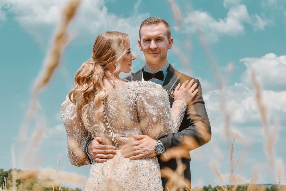 man in black suit jacket holding woman in white floral dress