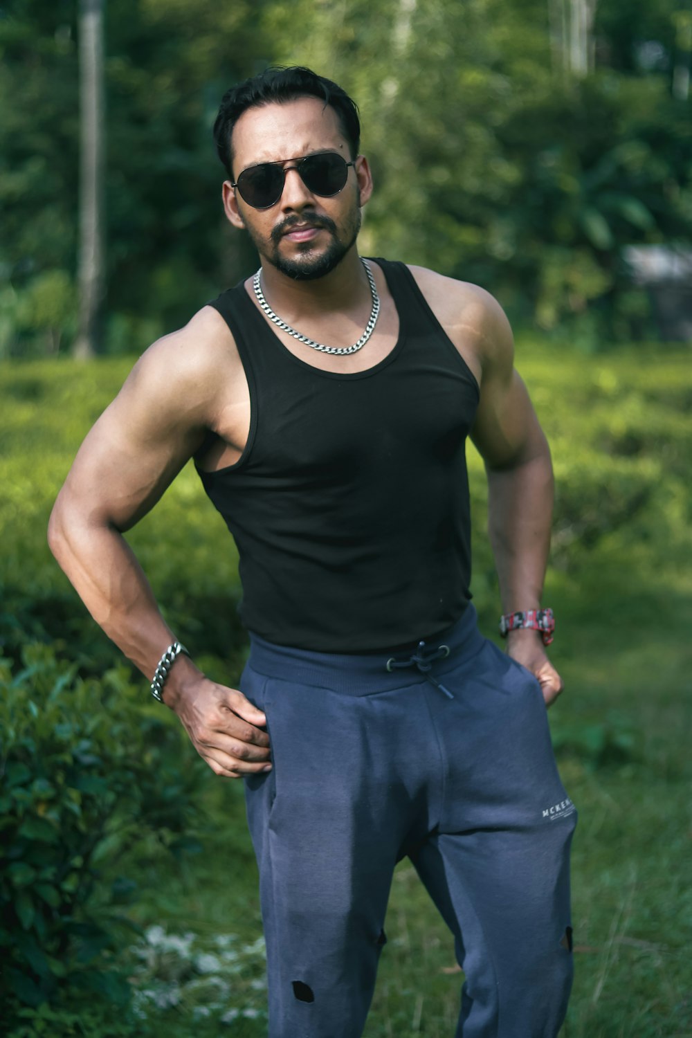 man in black tank top and blue denim jeans wearing black sunglasses