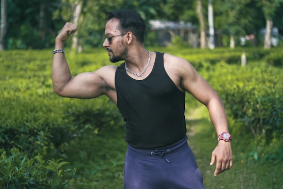 man in black tank top and blue shorts standing on green grass field during daytime