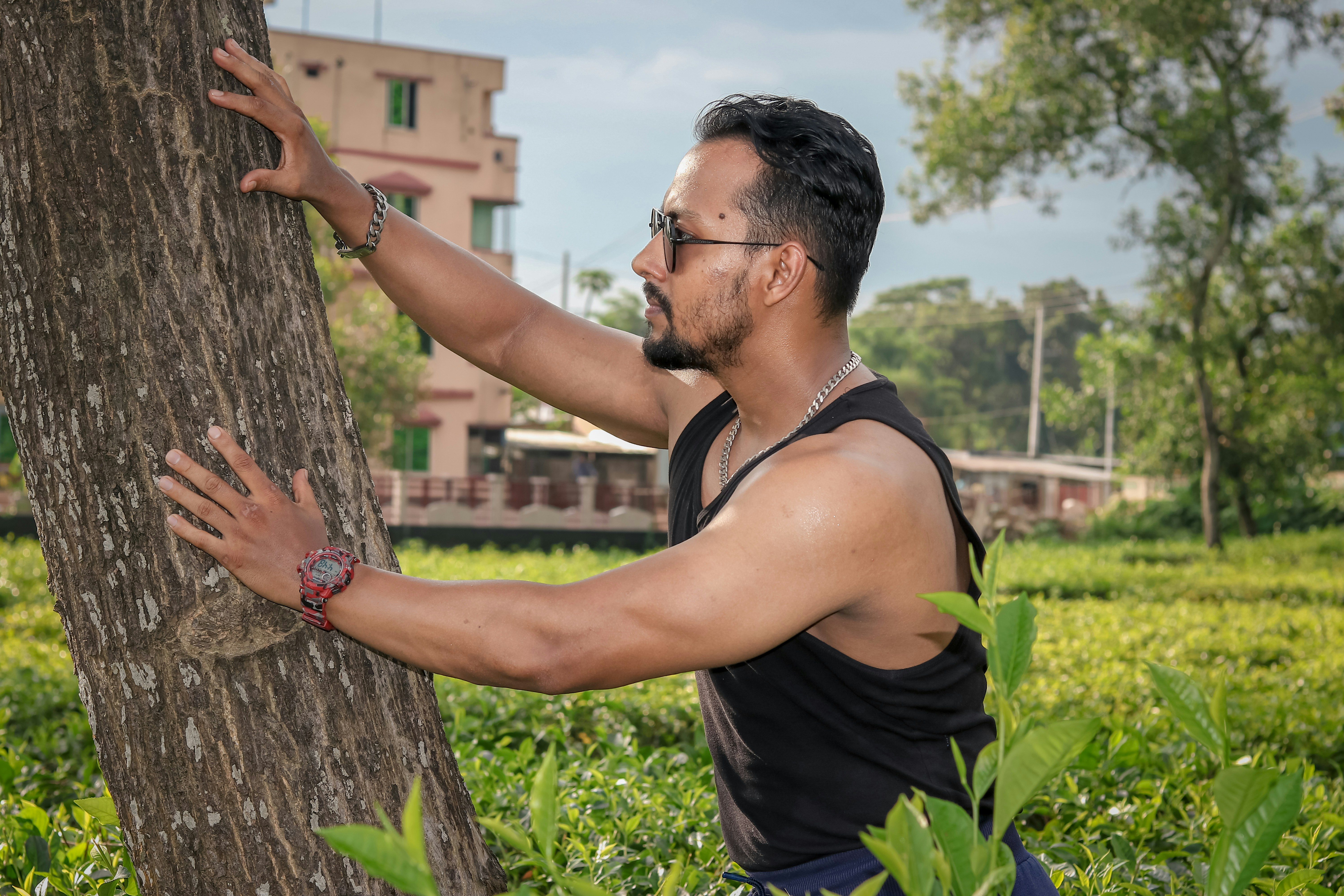 man in black tank top holding brown tree trunk during daytime