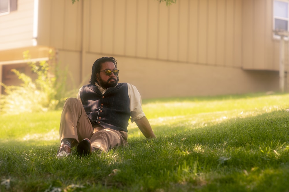 man in white shirt and brown pants sitting on green grass field