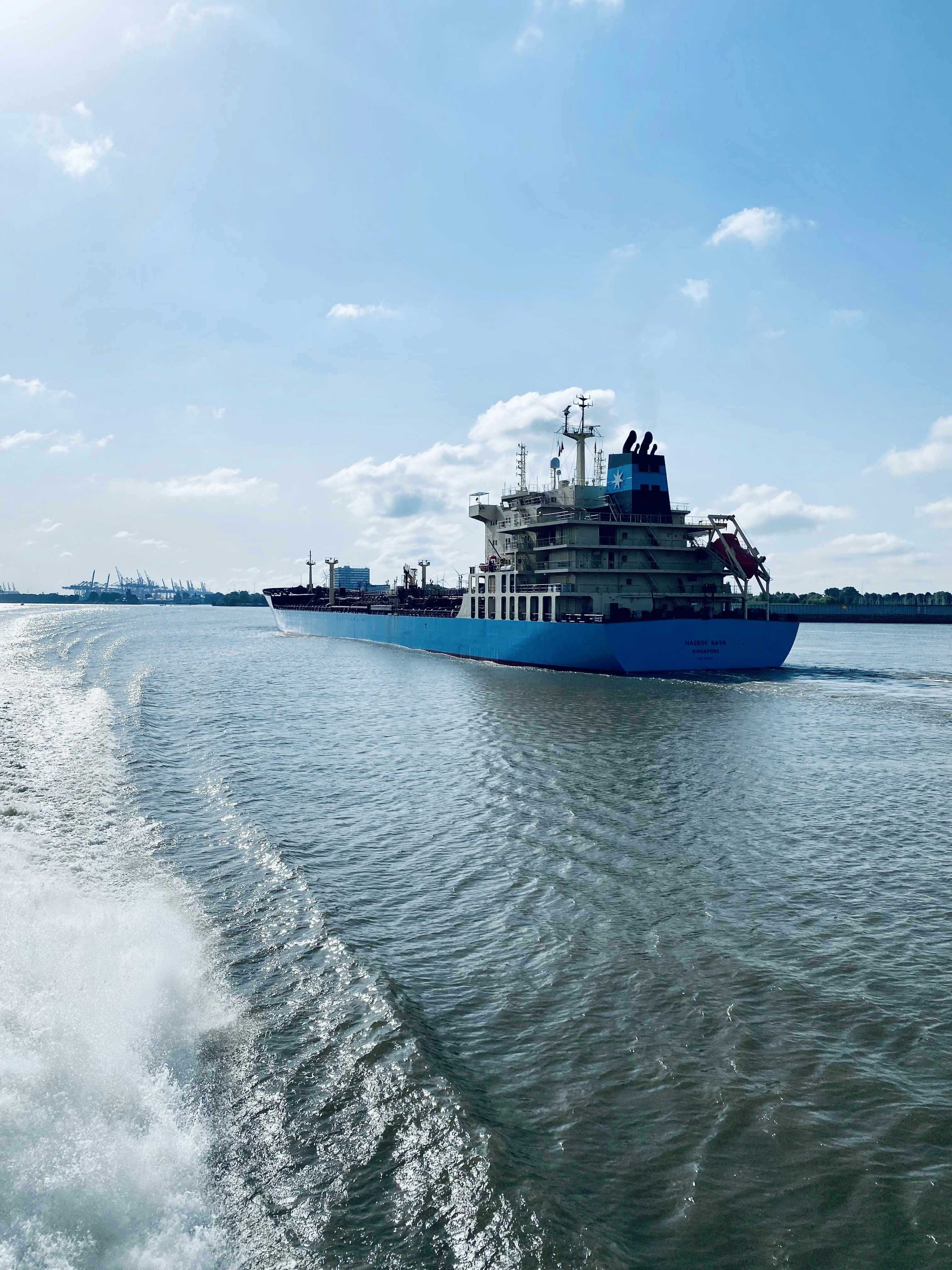 blue and white ship on sea under white clouds and blue sky during daytime