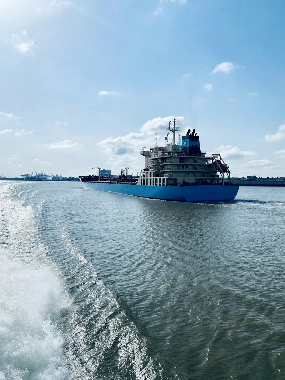 blue and white ship on sea under white clouds and blue sky during daytime