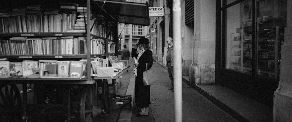 grayscale photo of man and woman standing near road