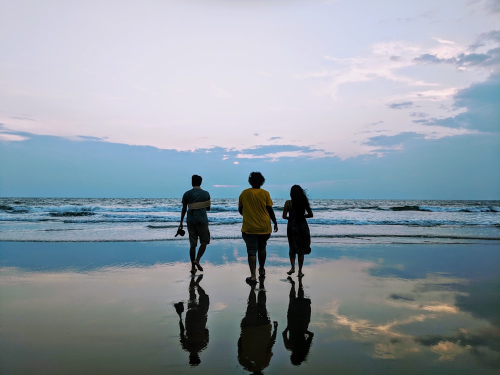 3 men walking on beach during daytime