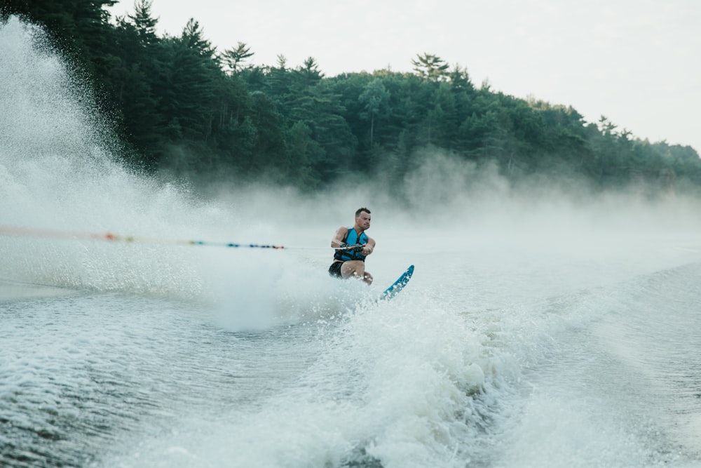 man in red jacket riding on blue kayak on body of water during daytime