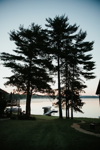 Peaceful lakefront property at sunrise with backyard dock and boat on still water.