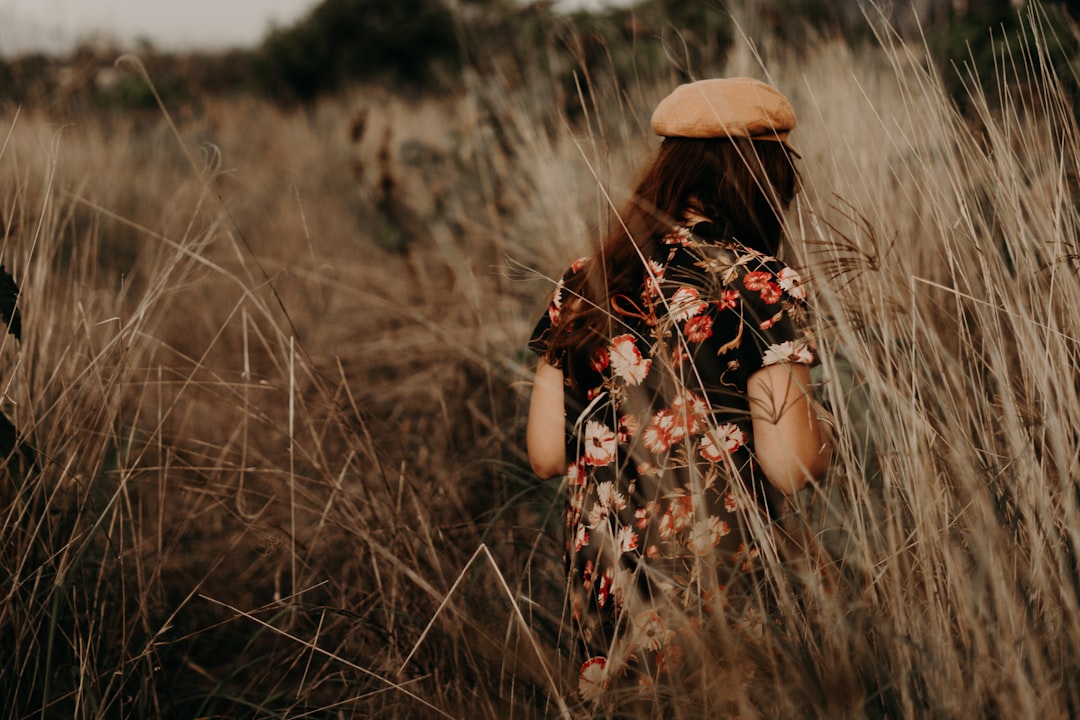 woman in brown hat standing on brown grass field during daytime