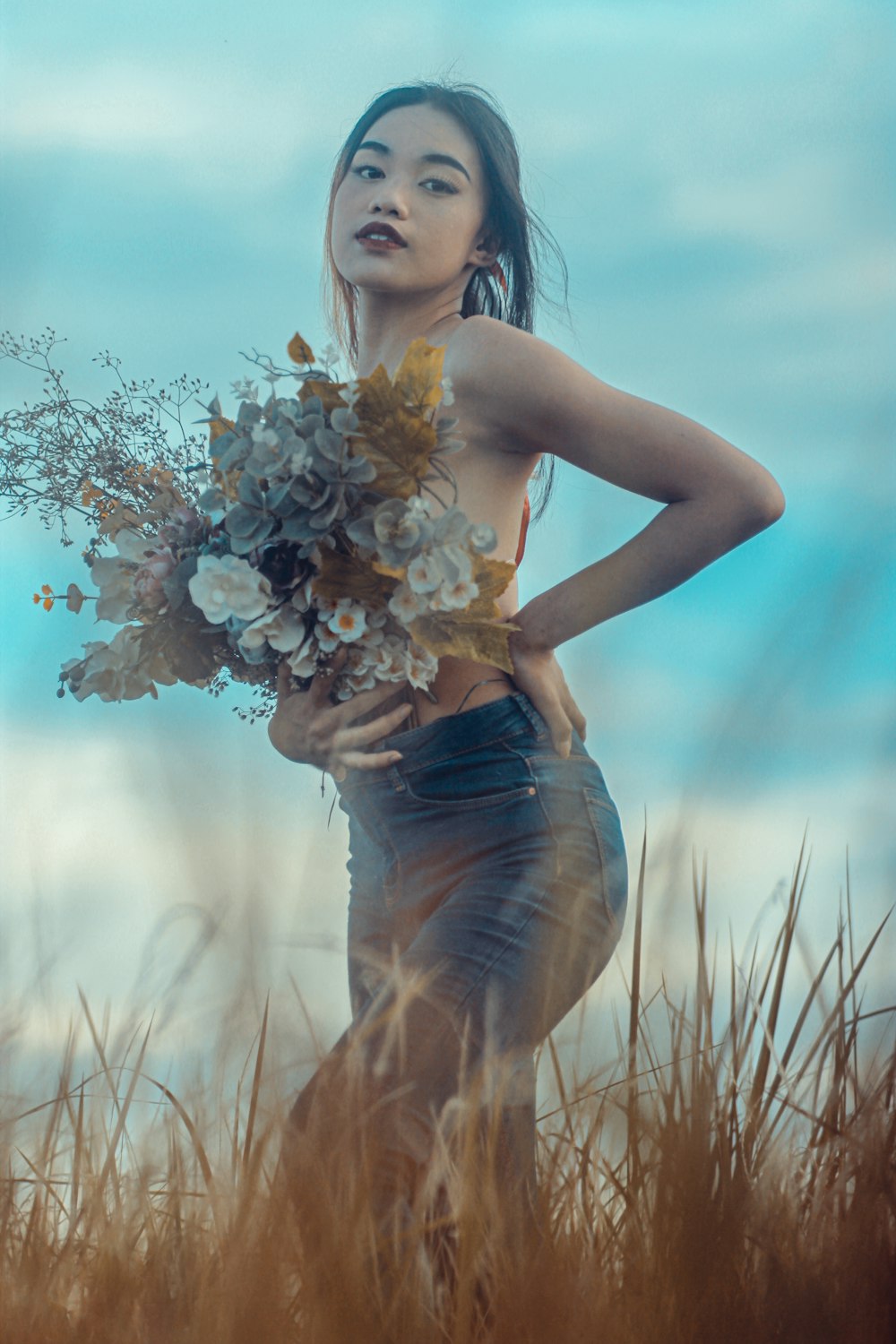 woman in blue denim shorts holding white flowers