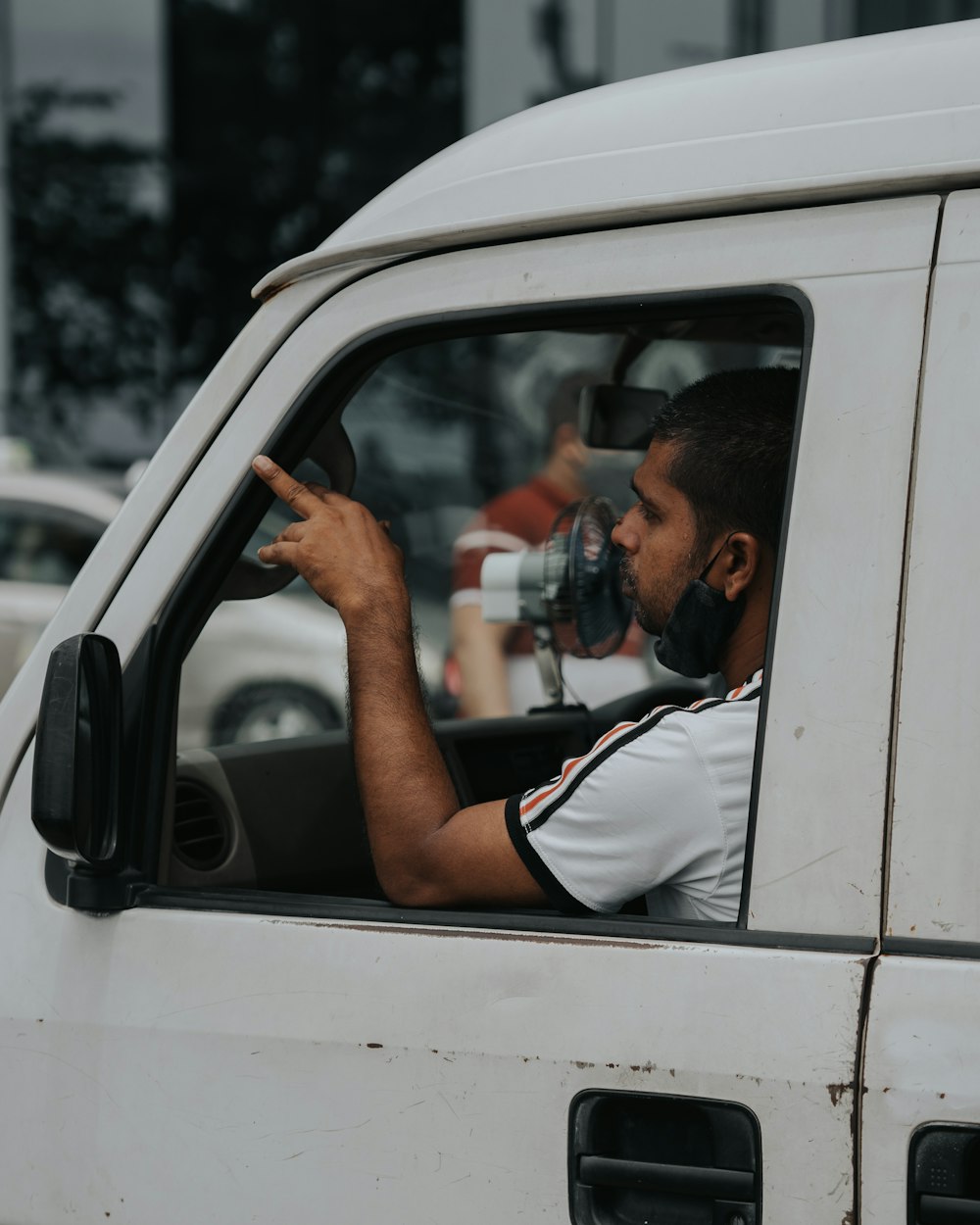 man in white t-shirt and black shorts sitting on car