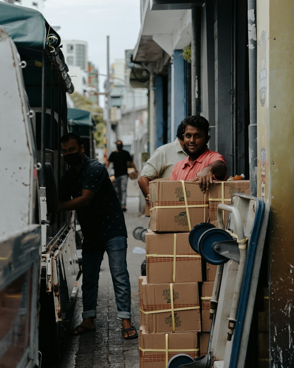 man in yellow t-shirt and black pants standing beside brown cardboard boxes