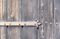 Close-up of original wooden schoolhouse door with vintage iron hinges and weathered paint.