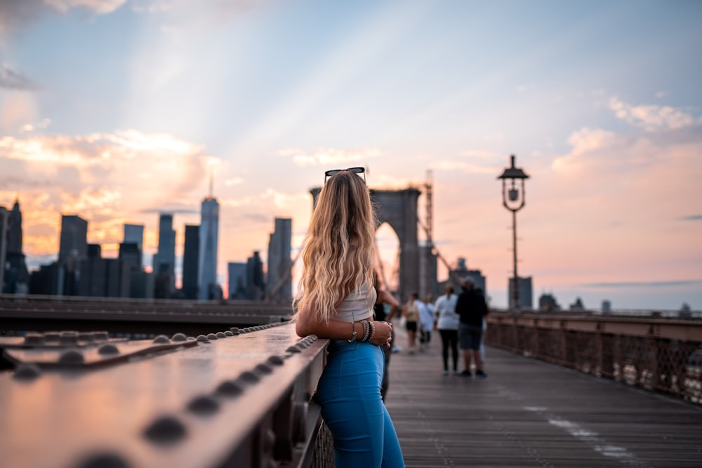 woman in blue denim jeans sitting on gray metal railings during daytime