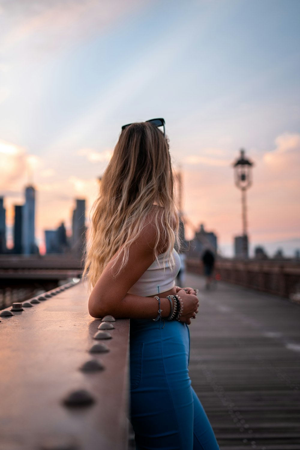 woman in white shirt and blue denim jeans sitting on concrete bench during daytime