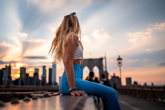 woman in white shirt and blue pants sitting on brown wooden table during daytime