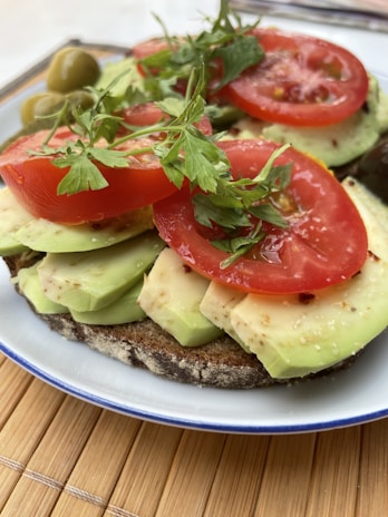 A vibrant plate of avocado toast garnished with cherry tomatoes and microgreens on a white plate.