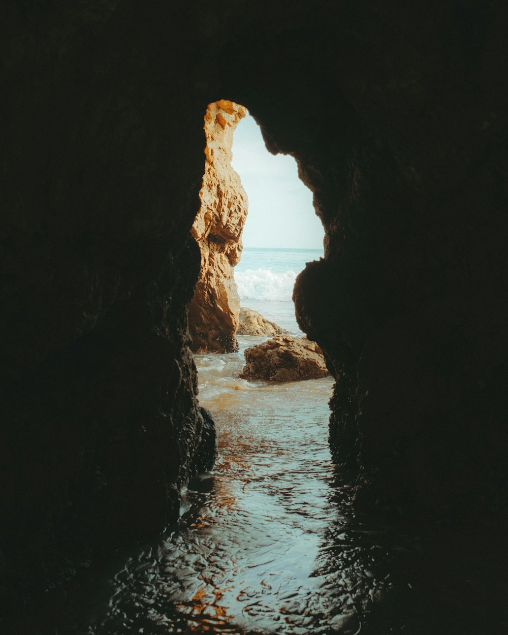 cave near body of water during daytime