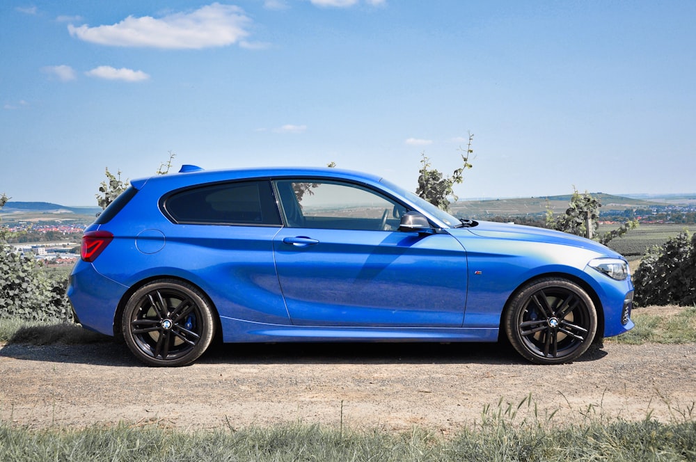 blue sedan on green grass field during daytime