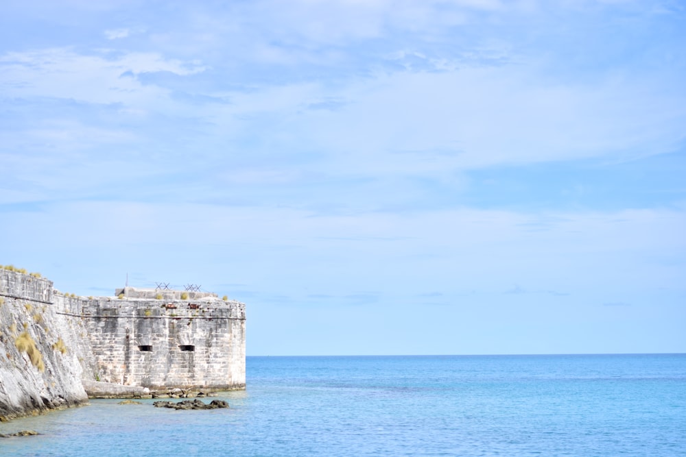 Graues Betongebäude auf blauem Meer unter blauem Himmel tagsüber