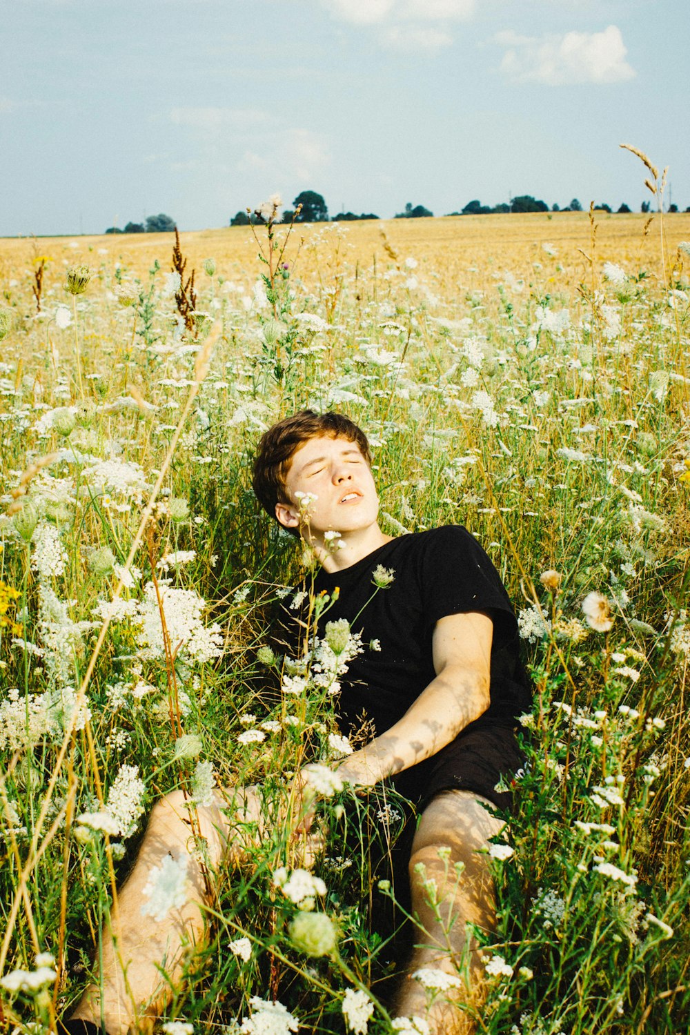 boy in black crew neck t-shirt sitting on green grass field during daytime