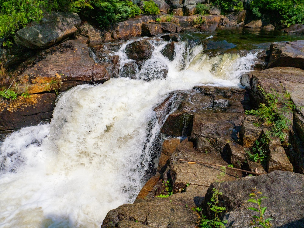 water falls on brown rocky mountain during daytime