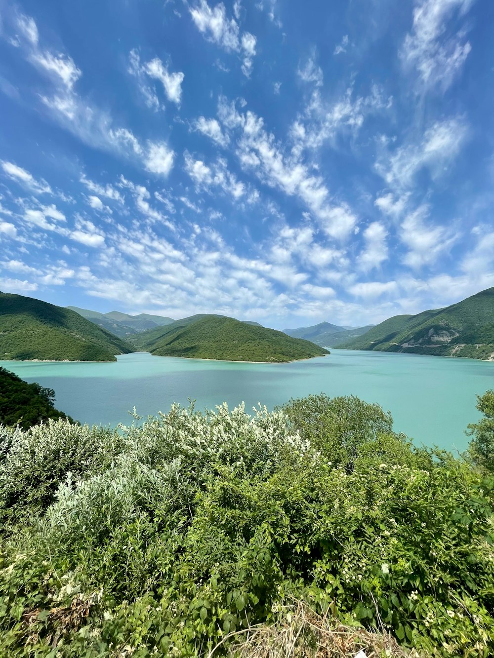 green mountains near body of water under blue sky during daytime