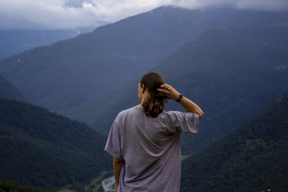 Mann in grauem T-Shirt tagsüber auf dem Gipfel des Berges