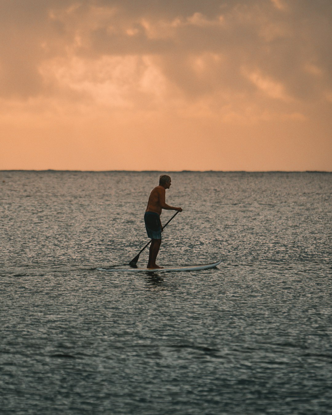 man in black wetsuit riding on boat during sunset