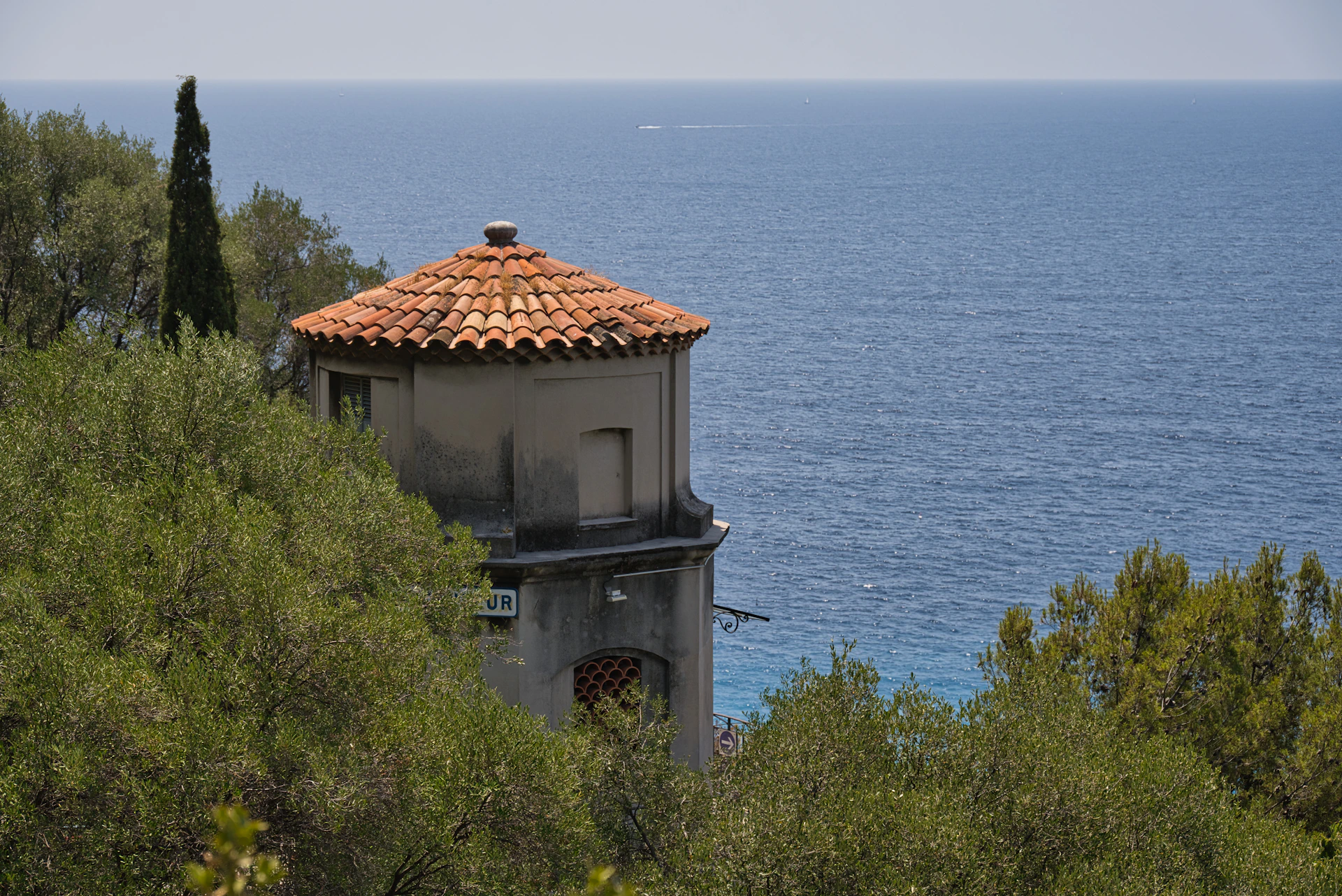 A serene coastal farmhouse with traditional Maharashtrian architecture nestled among lush greenery under a clear blue sky.