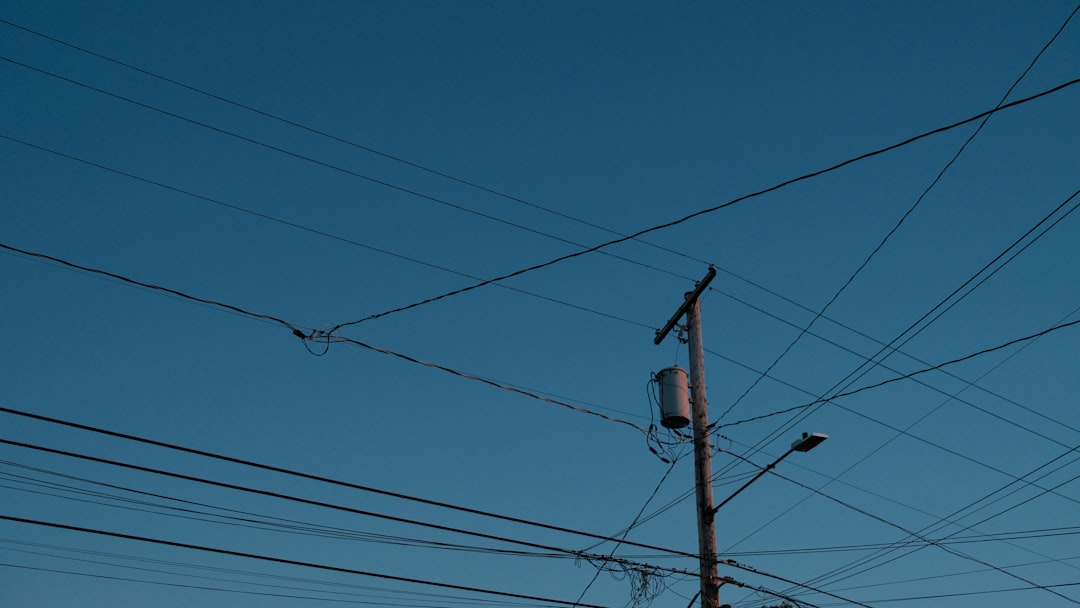 low angle photo of electric post under blue sky during daytime