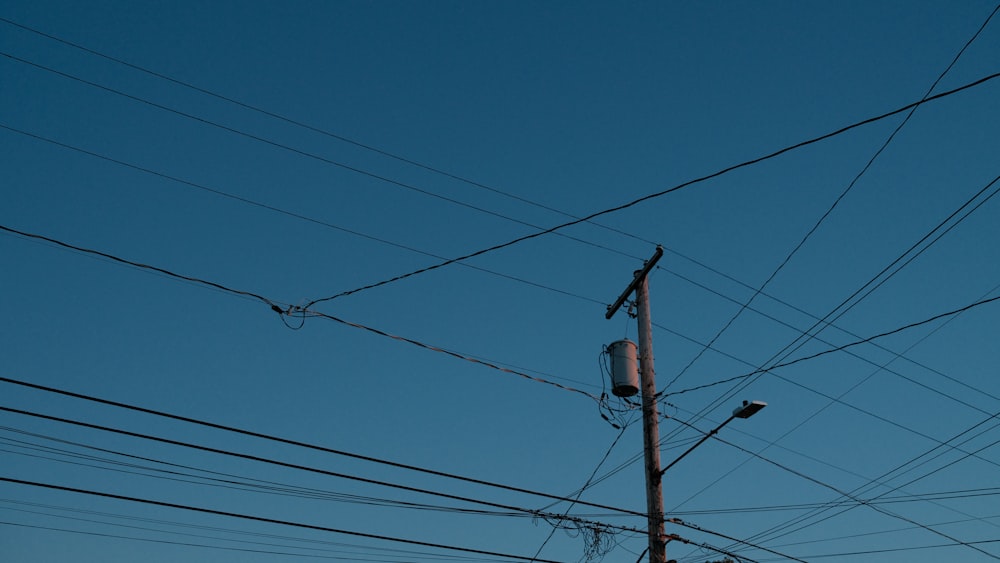 low angle photo of electric post under blue sky during daytime