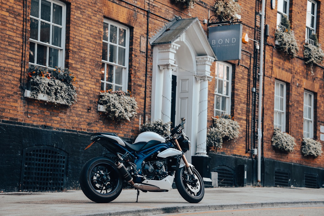 black and silver cruiser motorcycle parked beside brown brick building during daytime